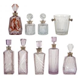 518   -  <p><span class="object_title">Lote de ocho botellas licoreras y una cubitera en cristal tallado de motivos florales y geométricos en tonalidades malva y burdeos con golletes y pomos en plata española punzonada, s.XX. </span>.<br></p>